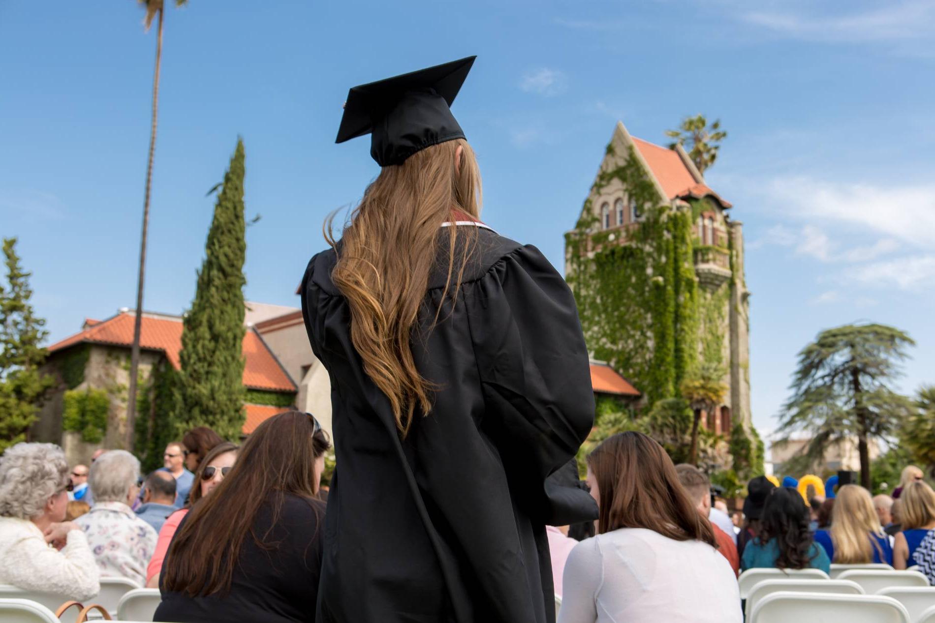 female sjsu graduate stands amongst crowd in front of 菠菜网lol正规平台's Tower Hall